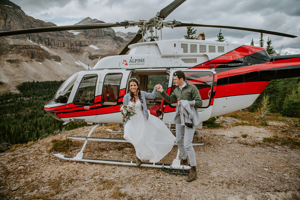 Couple landing at Mount Assiniboine during their helicopter elopement with their B.C elopement photographer 
