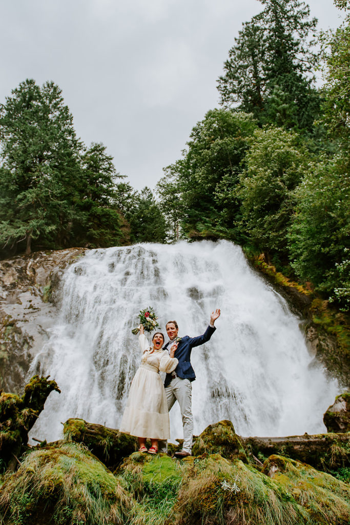 Couple celebrating in front of Chatterbox Falls in the Princess Louisa Marine Provincial Park during their British Columbia Elopement Package.