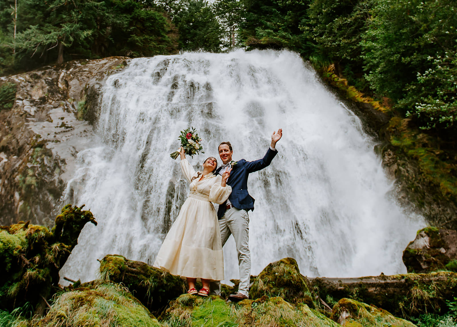 Couple celebrating in front of the waterfall during their British Columbia Adventure Elopement at Chatterbox falls.