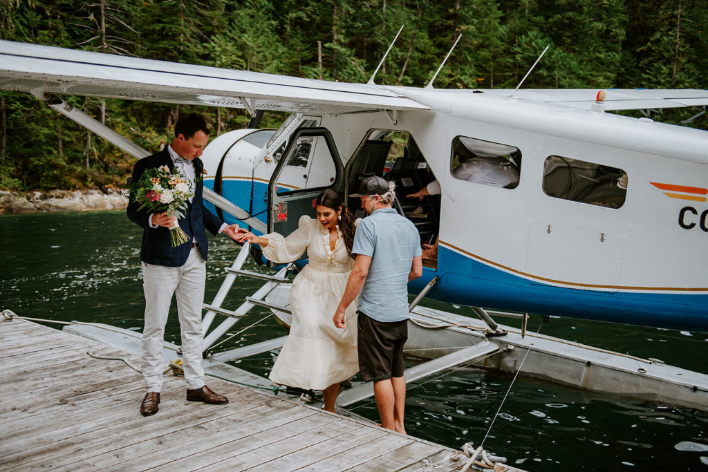 Bride getting out of Sunshine Coast Air Seaplane on the dock of Chatterbox Falls in the Princess Louisa Marine Provincial Park during her British Columbia Elopement Package.